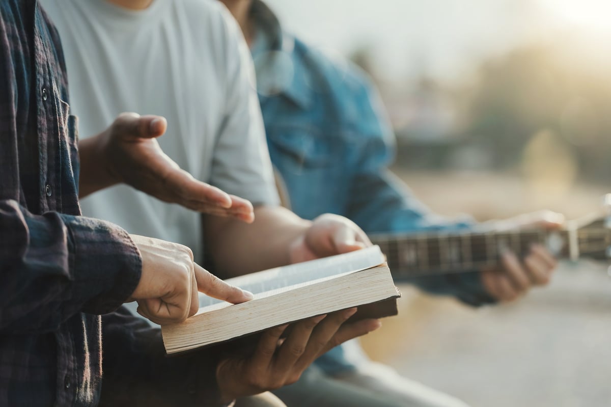 Bible study group reading and praying together in the park